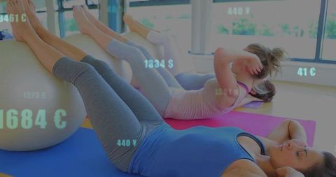 Women doing core crunches with stability ball on mats in bright fitness studio