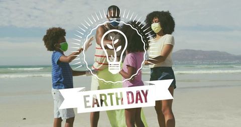 Family wearing face masks celebrating Earth Day on beach while collecting litter