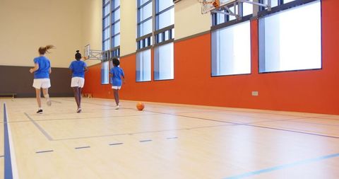 Energetic Girls Running Towards Basketball Hoop in Gym
