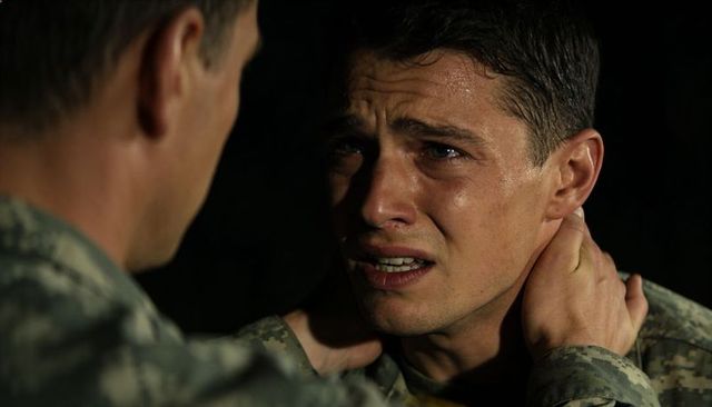 Emotional confrontation between soldiers, superior gripping tearful recruit in camouflage