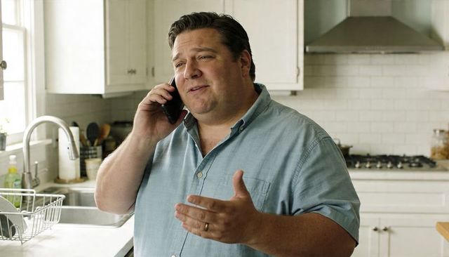 Smiling man talking on smartphone in bright modern kitchen, casual home conversation