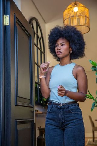 Woman in modern foyer with rattan lamp and black door