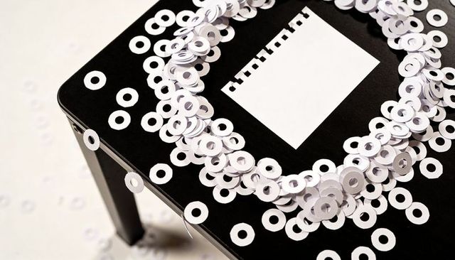 Paper ring wreath on black table with torn notepad minimalist monochrome concept