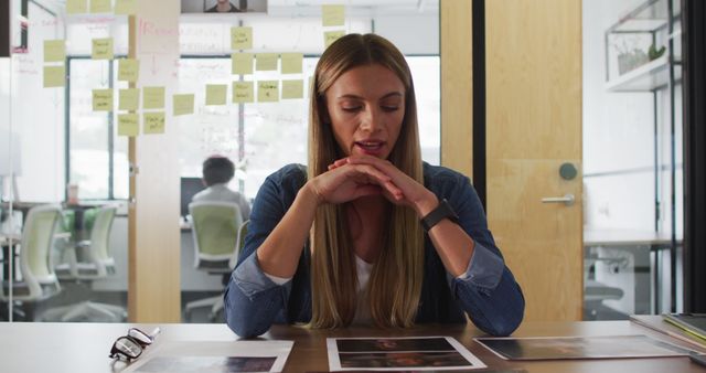 Pensive Female Office Worker Examining Photos at Desk - Download Free Stock Images Pikwizard.com