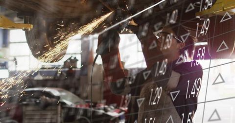 Automotive Mechanic Grinding Undercarriage with Sparks and Digital Data Overlay