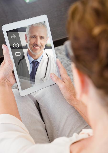 An elderly woman is using a digital tablet to have a video chat with a smiling doctor. Represents telemedicine and remote health consultations. Ideal for websites about telehealth, senior services, modern healthcare solutions, and virtual medical services.