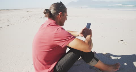 Senior Man Relaxing on Beach with Smartphone