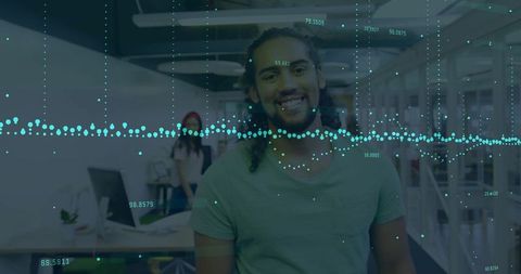 Smiling young professional standing in modern office with data overlay and teamwork