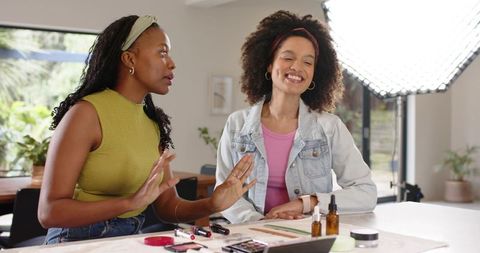 Diverse duo filming at-home makeup tutorial with softbox lighting and cosmetic palette