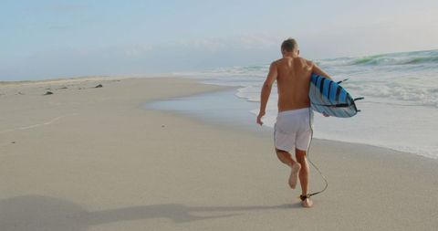 Surfer Running Toward Ocean with Surfboard