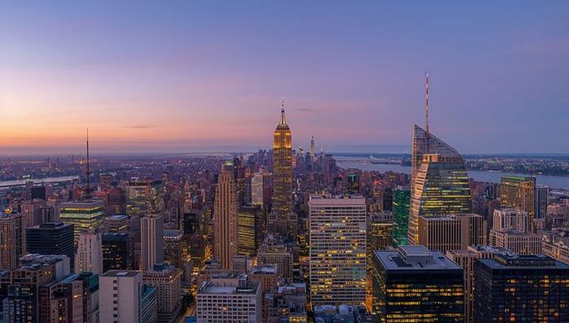 Panoramic Midtown Manhattan skyline at dusk featuring Empire State Building glowing spire