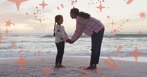Mother and Daughter Holding Hands on Beach at Sunset