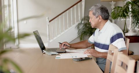 Senior Man Managing Finances with Laptop at Home