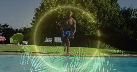 Muscular man walking toward backyard pool in blue trunks with tropical light ring