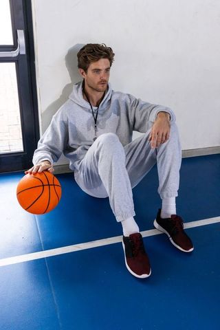 Male Athlete Resting on Gym Floor with Basketball