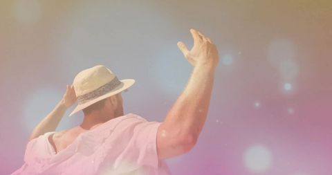 Man in Fedora and Pink Top Against Pastel Bokeh Backdrop