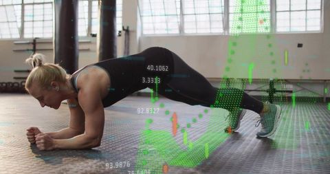 Female athlete holding forearm plank with green data overlay in industrial gym