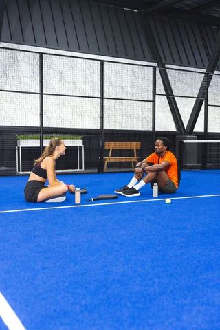 Diverse Fitness Partners Relaxing after Padel Game on Outdoor Court