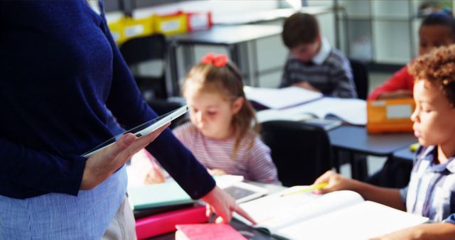 Teacher Assisting Elementary Students with Schoolwork in Classroom - Download Free Stock Images Pikwizard.com