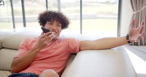 Young Man Relaxed on Couch Using Smartphone at Home