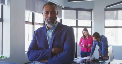 Confident Businessman in Modern Office with Colleagues in Background