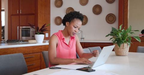 Woman Managing Finances Online with Laptop in Modern Kitchen