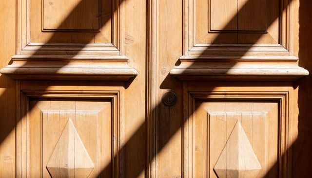 Sunlit antique wood double door with raised panels moulding and central keyhole