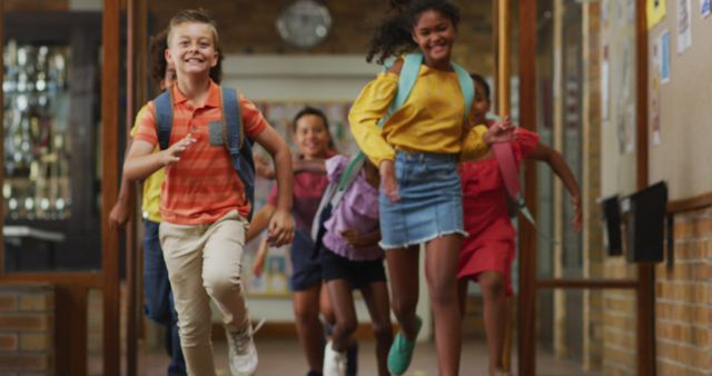 Diverse group of happy schoolchildren wearing backpacks, running fast through school corridor. children in primary school.