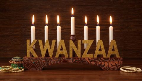 Celebrating kwanzaa with carved kinara holding seven lit candles and gold kwanzaa letters