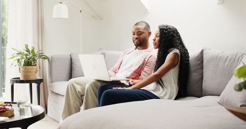 Smiling Couple Video Calling on Laptop in Bright Living Room