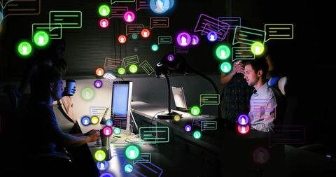 Working late with digital notification overload, team collaborating under moody office lighting