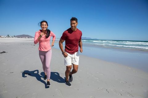 Diverse Friends Enjoying Jogging on Sandy Beach in Sunlight