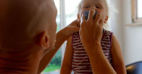 Father Gently Cleans Daughter's Face at Home