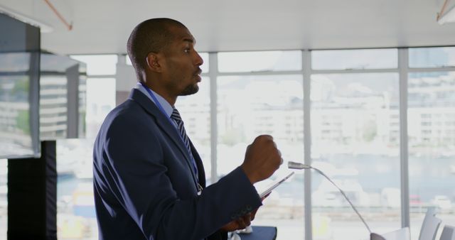 African American businessman in a suit speaks and gestures at a conference with a tablet. - Download Free Stock Photos Pikwizard.com