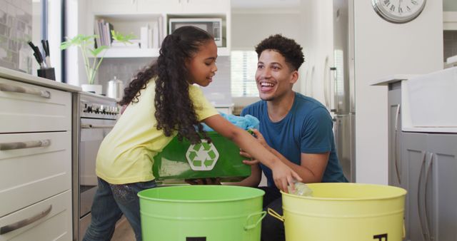 Happy biracial father and daughter sorting waste together. domestic lifestyle, spending free time at home.