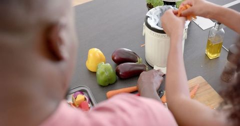 Couple Composting in Eco-Friendly Kitchen with Fresh Vegetables