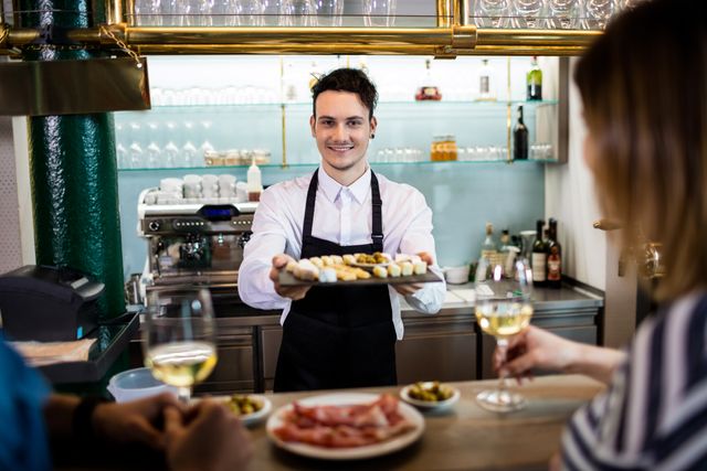 Young bartender serving food to customers at restaurant counter. Ideal for illustrating hospitality, customer service, dining experiences, and restaurant settings. Suitable for use in marketing materials, websites, and advertisements related to food and beverage industry.