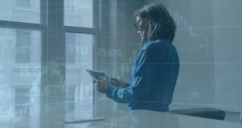 Woman Using Tablet Amidst Financial Graphs in Modern Office
