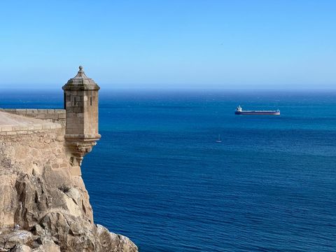 Historic Watchtower Overlooking Tranquil Sea with Ship on Horizon