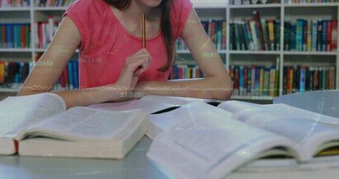 Teenage girl deep in study at library with textbooks