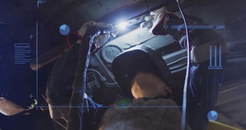 Female Mechanic Welding Undercarriage Under Vehicle Wearing Helmet and Gloves in Garage