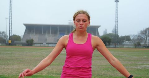 Female Athlete Stretching at Track Stadium