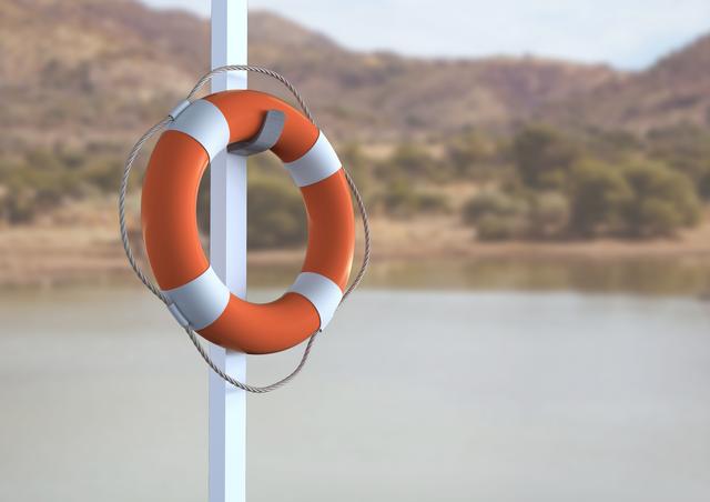 Close up of lifebuoy hanging on pole near calm lake with blurred background of lush forest and hills. Great for illustrating outdoor safety, water-based activities, lifeguard services, nature reserve safety measures, and serene landscape visuals.