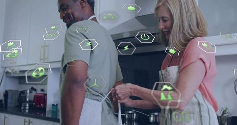 Couple Tying Apron in Kitchen with Green Energy Icons Representing Eco-Friendly Living
