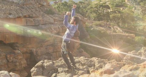 Caucasian Man Standing on Rocky Cliff Celebrating Achievement