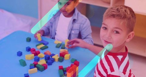 Two boys building with wooden blocks at colorful activity table in preschool classroom