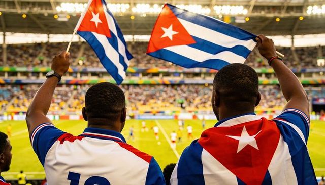 Cuban fans waving national flags, cheering during soccer match in packed stadium