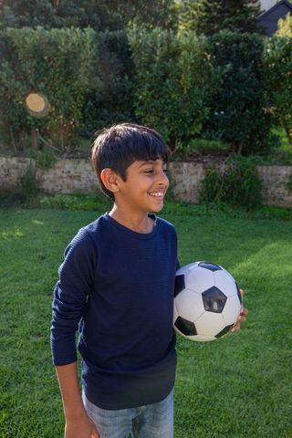 Smiling Boy in Garden with Soccer Ball Embracing Outdoor Play