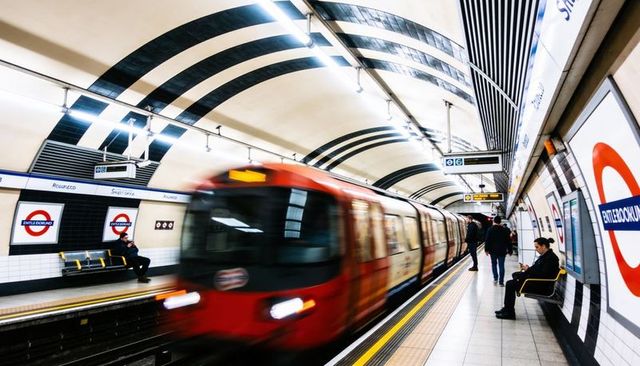 Rushing red london underground train with motion blur on platform and waiting commuters