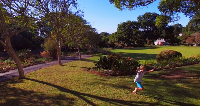 Boy Running on Green Lawn in Sunny Park with Trees - Download Free Stock Images Pikwizard.com